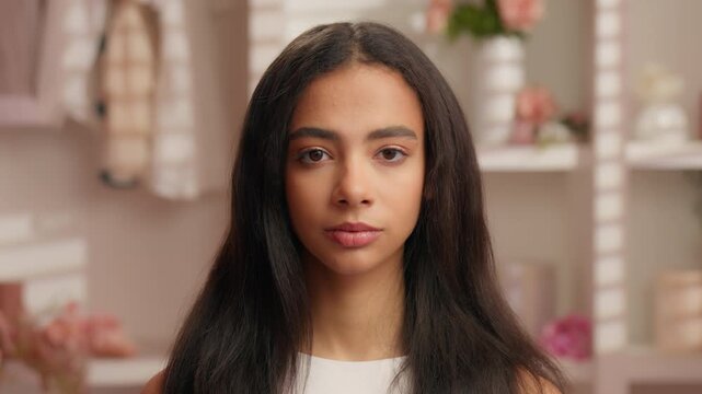Headshot pretty charming serious Latina Hispanic young woman looking at camera in pink glamour bathroom American Hispanic girl with perfect skin face natural hair care beauty procedure female feminity