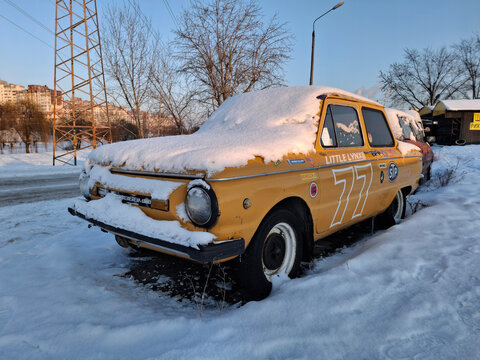 Old car Zaporozhets, soviet automobile is parked on snow-covered parking lot
