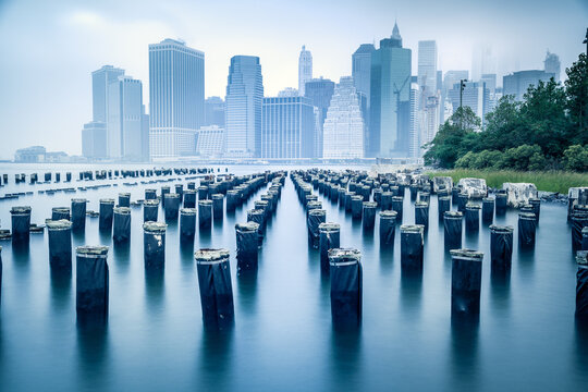 City skyline and wooden posts viewed from a waterfront park, New York, New York City, USA