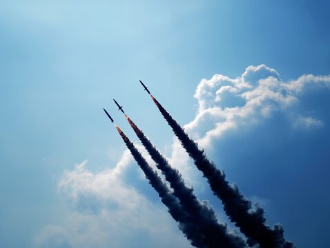 Three missiles launching into blue sky with dramatic smoke trails