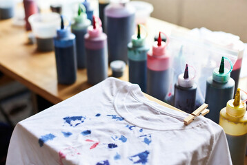 Fototapeta premium A white t-shirt is being tie-dyed with various colored dyes on a table.
