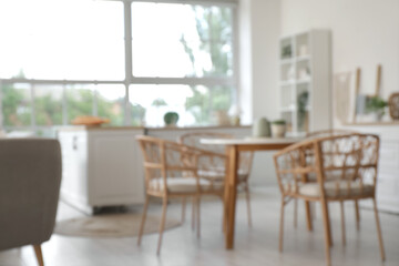 Fototapeta premium Blurred view of light kitchen with counters and dining table