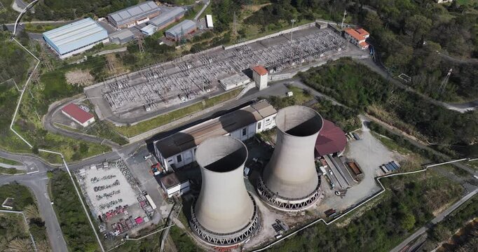 Larderello, Italy - 15 April 2026: Aerial view of Enel Green Power - Centrale Geotermica di Larderello with its iconic cooling towers and electrical substation surrounded by green hills.