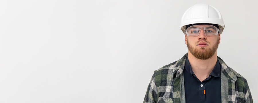 Portrait of a male builder. Engineer in overalls and helmet on a light background. Space for text.