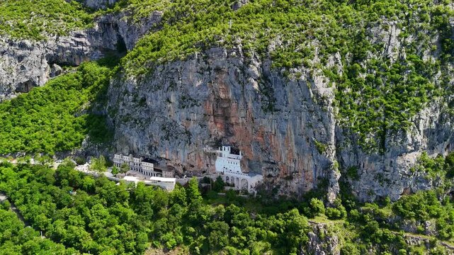 Aerial drone view of Ostrog Monastery in Montenegro. Orthodox Christian monastery built into a vertical rock cliff, famous pilgrimage site.