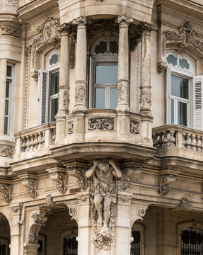 Cuba, Havana.  Architectural detail of relief sculpture, of a heroic figure holding up a corner balcony.