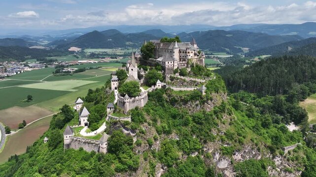 Cinematic drone footage capturing Hochosterwitz Castle on hilltop, fortified walls, dramatic cliffs, summer colors, sweeping aerial movement, historical landmark atmosphere