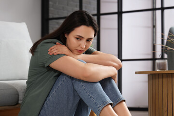 Depressed young woman sitting at home
