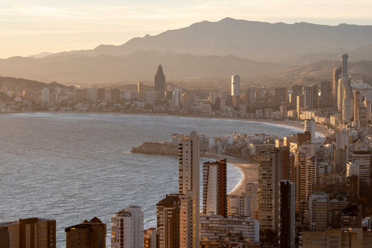 Urban skyline cityscape at warm sunset along the sea coast with mountains behind Benidorm Spain evening atmosphere for real estate