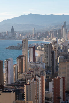 Highrise apartments form a skyline cityscape on the sea coast with mountains and haze around Benidorm Spain Mediterranean resort housing