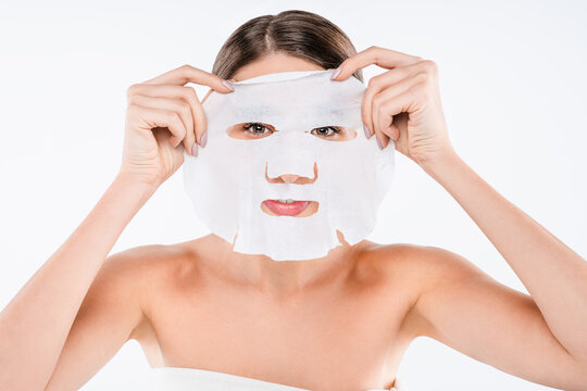 Young woman applying refreshing sheet face mask isolated on white background, skincare routine, hydration treatment, facial care and beauty wellness concept