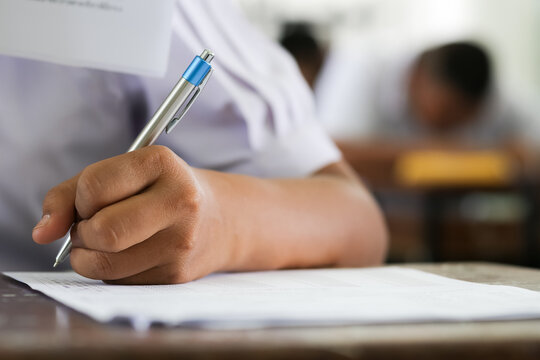 Selective Focus of Student's Hand Writing on Answer Sheet in Classroom