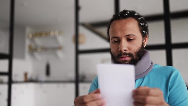 Man in neck brace reading hospital bill letter, shocked by high medical costs