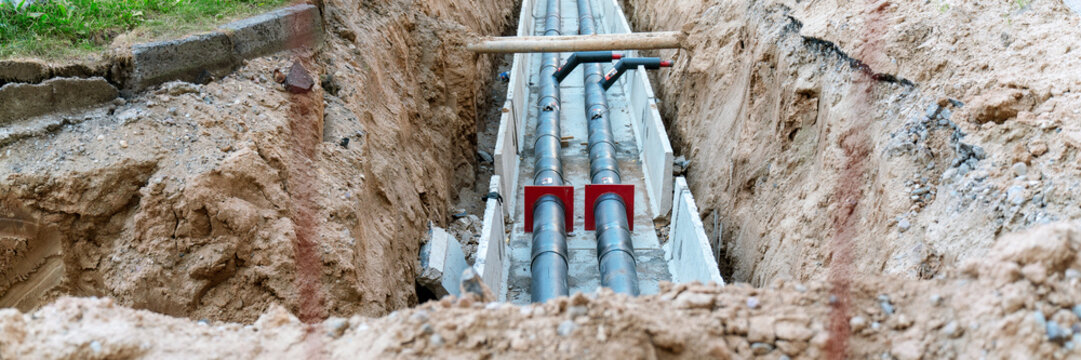 New pipes laying in an open trench, representing ongoing groundwork and utility installation at a construction site