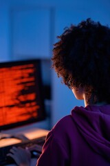 Fototapeta premium Person typing at desktop with red code on large monitor