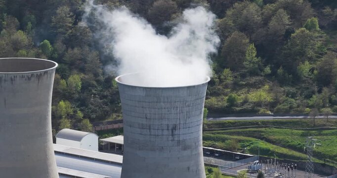 Larderello, Italy - 15 April 2026: Aerial view of Enel Green Power Centrale Geotermica di Larderello with steam rising from cooling towers against green hills.