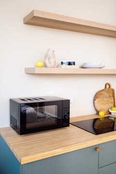 Modern kitchen with microwave and induction cooktop on wooden countertop