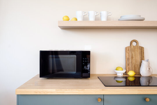 Modern kitchen interior with microwave, electric stove, wooden counter