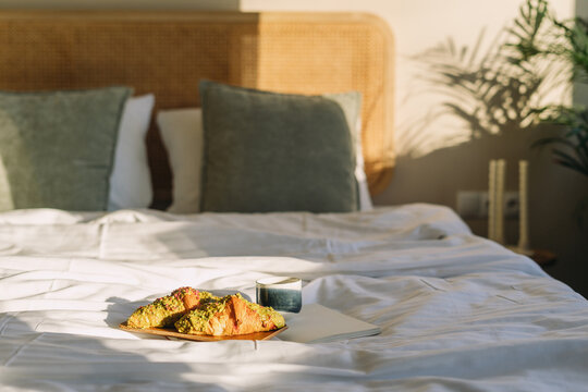Cozy bedroom with bed, breakfast tray, and sunlight in a hotel room setting