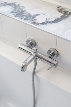 Sleek chrome bath faucet and flexible shower head in modern bathroom
