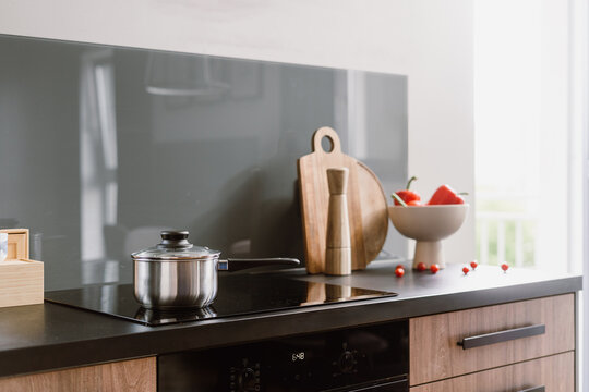 Modern kitchen with induction hob and cooking items set in an apartment space