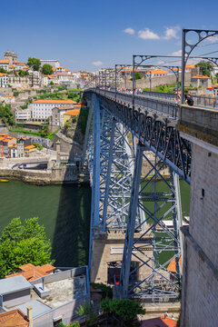 Porto, Portugal - 13 July 2021: View of the Dom Luis I Bridge, a metallic marvel spanning the Douro River, connecting the vibrant cityscape under a clear blue sky.