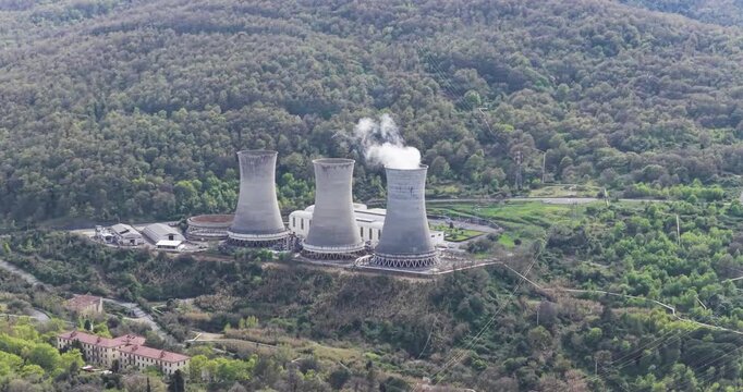 Larderello, Italy - 15 April 2026: Aerial view of Enel Green Power geothermal plant with cooling towers and steam surrounded by the green hills of Tuscany.