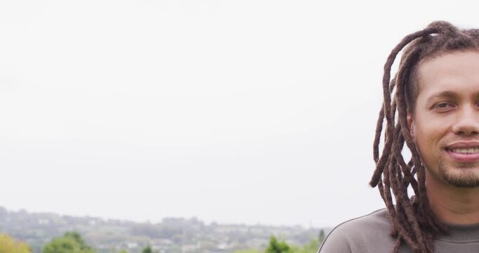 African American man in gray crewneck smiling, laughing as camera pans right over hills, copy space