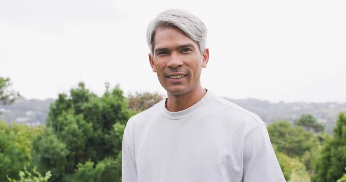 African American man reacting to camera tightening, smiling, laughing outside with trees hills