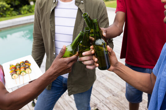 Men offering skewers sparking poolside toasting for cookout, food icons orbiting raised bottles
