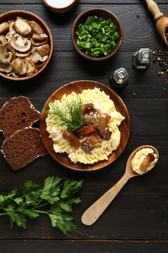 Plate of tasty banosh, mushrooms and bread on black wooden background