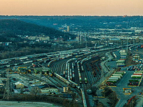 Cincinnati, United States - 27 February 2026: Aerial view of a sprawling railyard, where lines of trains converge under the warm hues of the setting sun.
