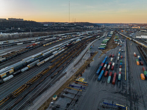 Cincinnati, United States - 27 February 2026: Aerial view of a sprawling railyard, a symphony of steel and vibrant containers under the soft hues of the setting sun.