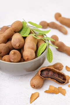 Bowl of tasty tamarinds and leaf on white background