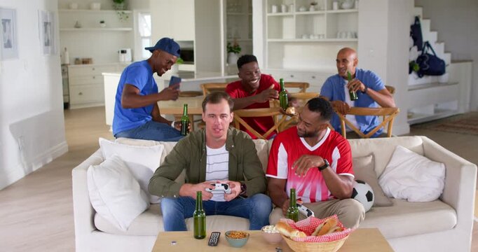 Diverse male friends playing game in living room, left man holding controller creating excitement