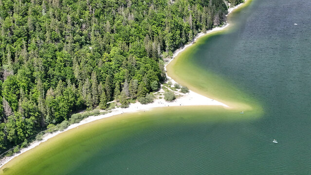 Aerial view of the meeting of emerald waters and sandy shorelines fringed by the verdant forest of Lac de Joux, Le Lieu, Vaud, Switzerland.
