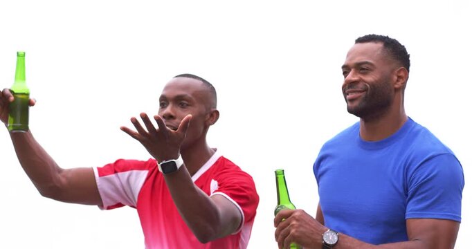Two men of African descent sitting on bench, reacting to off-camera moment, toasting green bottles