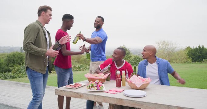 Diverse male friends gathering around table on deck postgame, arranging skewers, passing bottles
