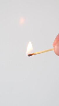 Macro shot of striking a match on a box and burning flame on white background
