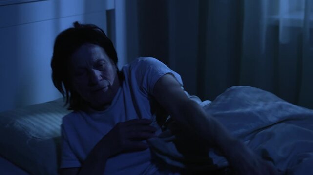 Elderly woman having heart attack lying in bed at night