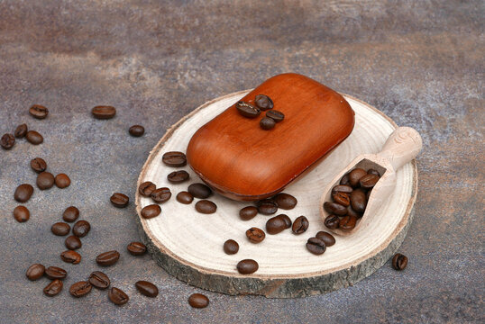Natural coffee soap with coffee beans and wooden scoop on a rustic tree slice.