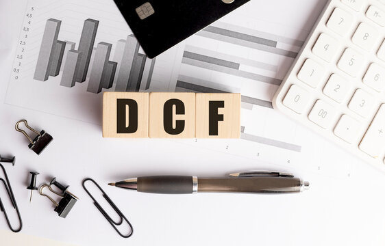 Dcf text on wooden blocks with credit card calculator and financial charts on desk finance valuation concept
