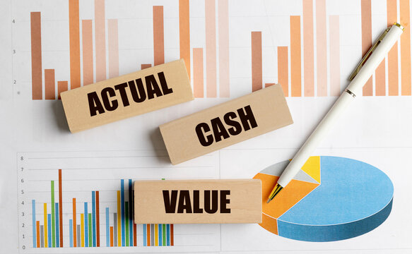 Actual cash value text on wooden blocks with pen and financial charts on desk business finance concept
