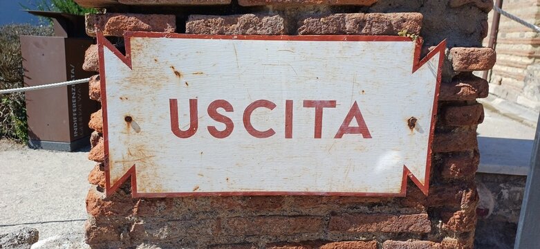 AUSGANG! Historisches Metallschild mit der Aufschrift Uscita an einer antiken Ziegelmauer in Pompeji