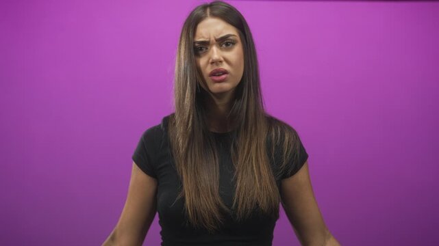 Woman with hands to temples and open palms, furrowed brow and puzzled facial expression, visible arms and palms in studio; confusion.