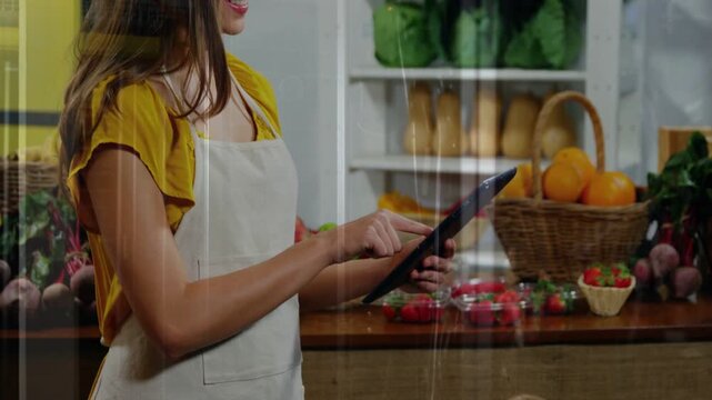 Produce attendant tapping tablet, showing animated price tags and charts over fruit, checking stock