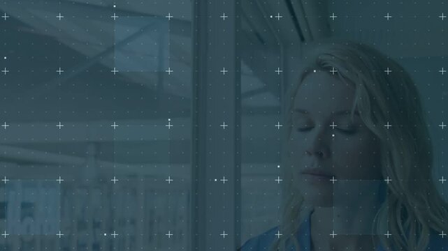 Opening eyes, smiling, woman in blue top standing at atrium window with dotted grid, copy space
