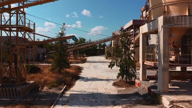 Abandoned industrial factory with rusty conveyor belts and decaying concrete silos