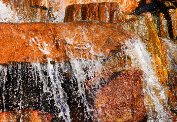 Waterfall close-up background, texture. Water flowing over rocky stones, splashes drops. Flow of water with texture stones. Water and roughness of stone. natural waterfalls or artificial cascades © MaxSafaniuk