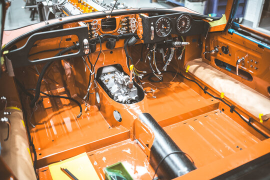 Classic car interior undergoing restoration with exposed engine and wiring